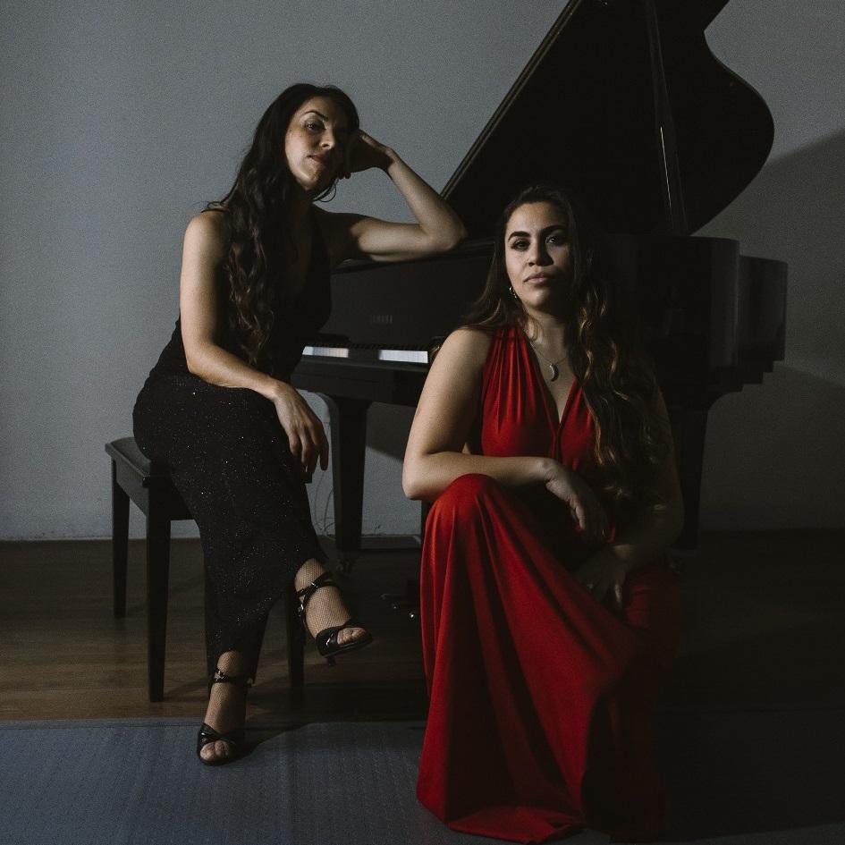Mariana Airaudo y Manuela Hernández. Mariana Airaudo sentrada en el paino y Manuela Hernández sentada en una silla a su lado.