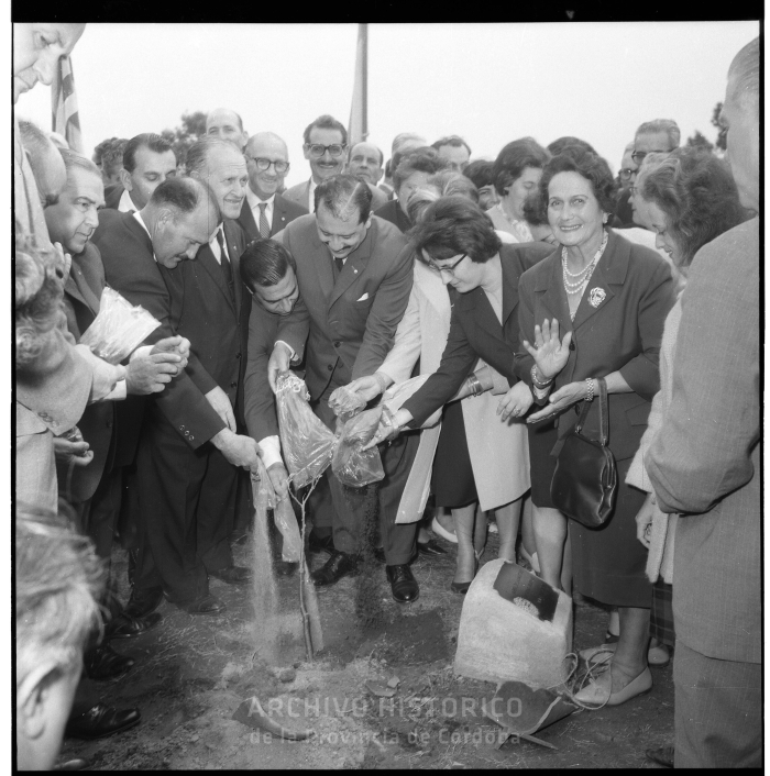 Foto de participantes del acto plantando un árbol en el espacio verde del monumento.