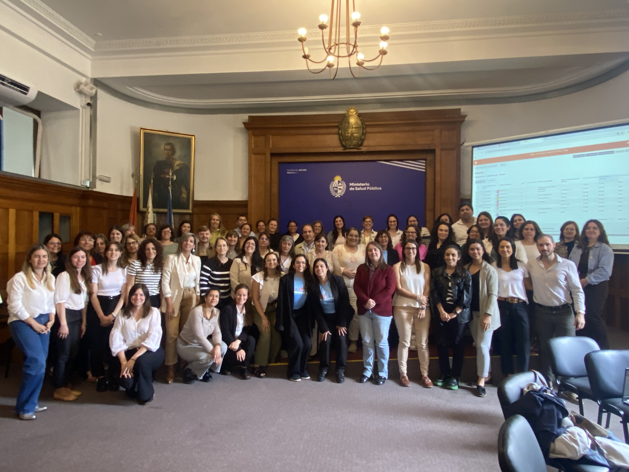 Foto grupal con personas de pie. Fondo institucional.
