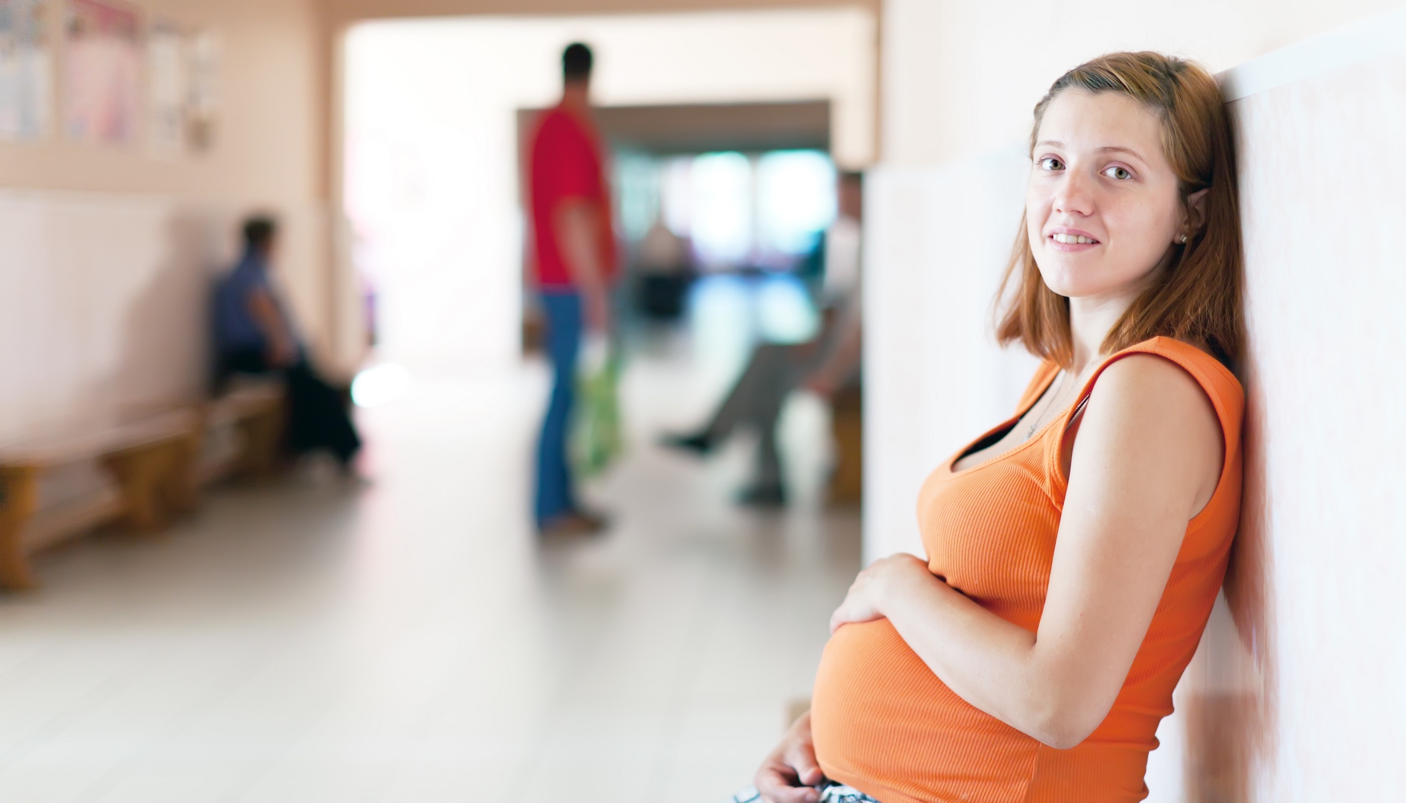 Mujer embarazada sentada contra una pared
