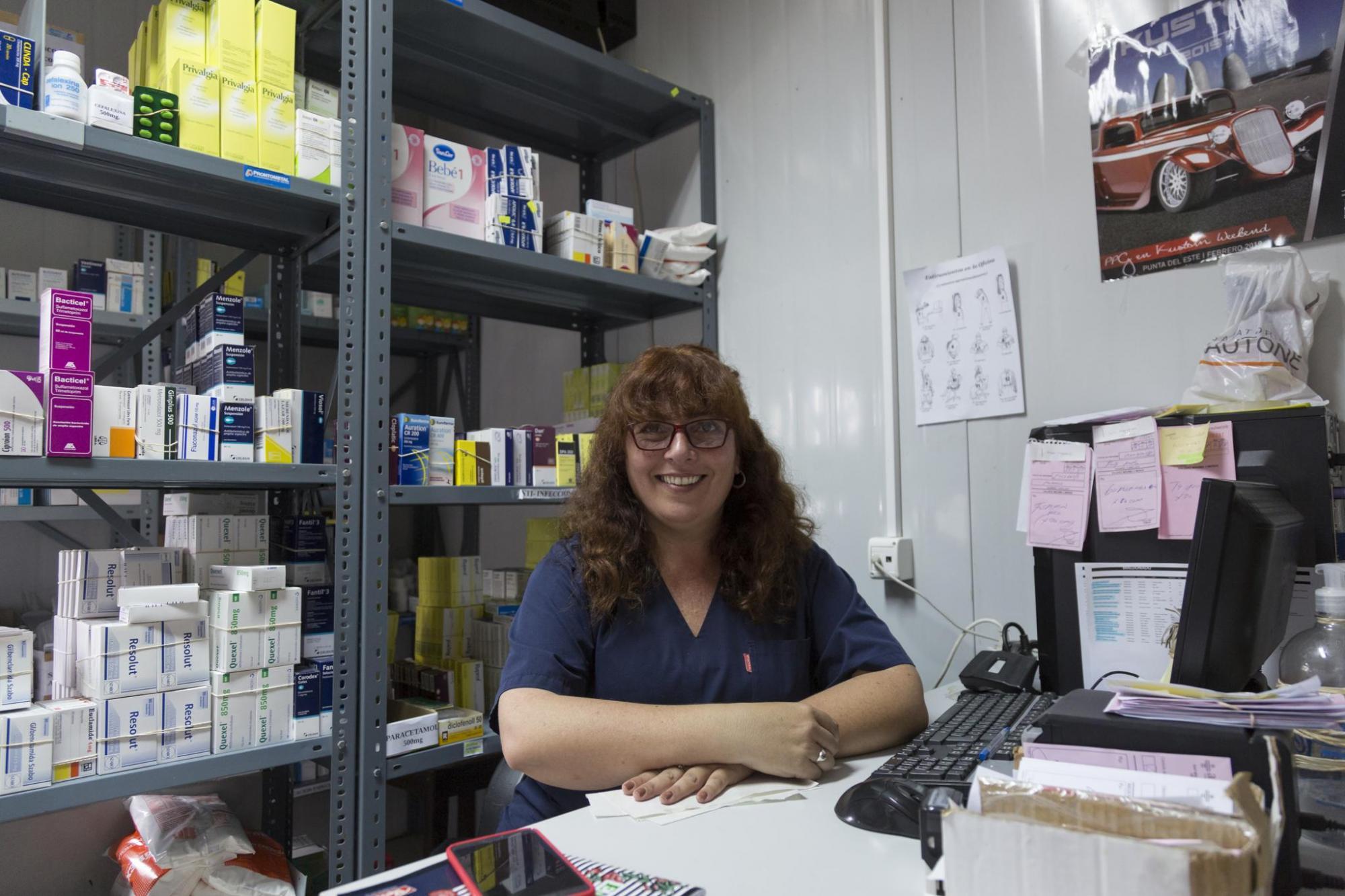 Mujer sentada delante de estantería con medicamentos