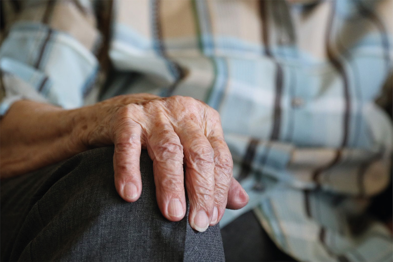 Mano de una persona mayor apoyada en su rodilla
