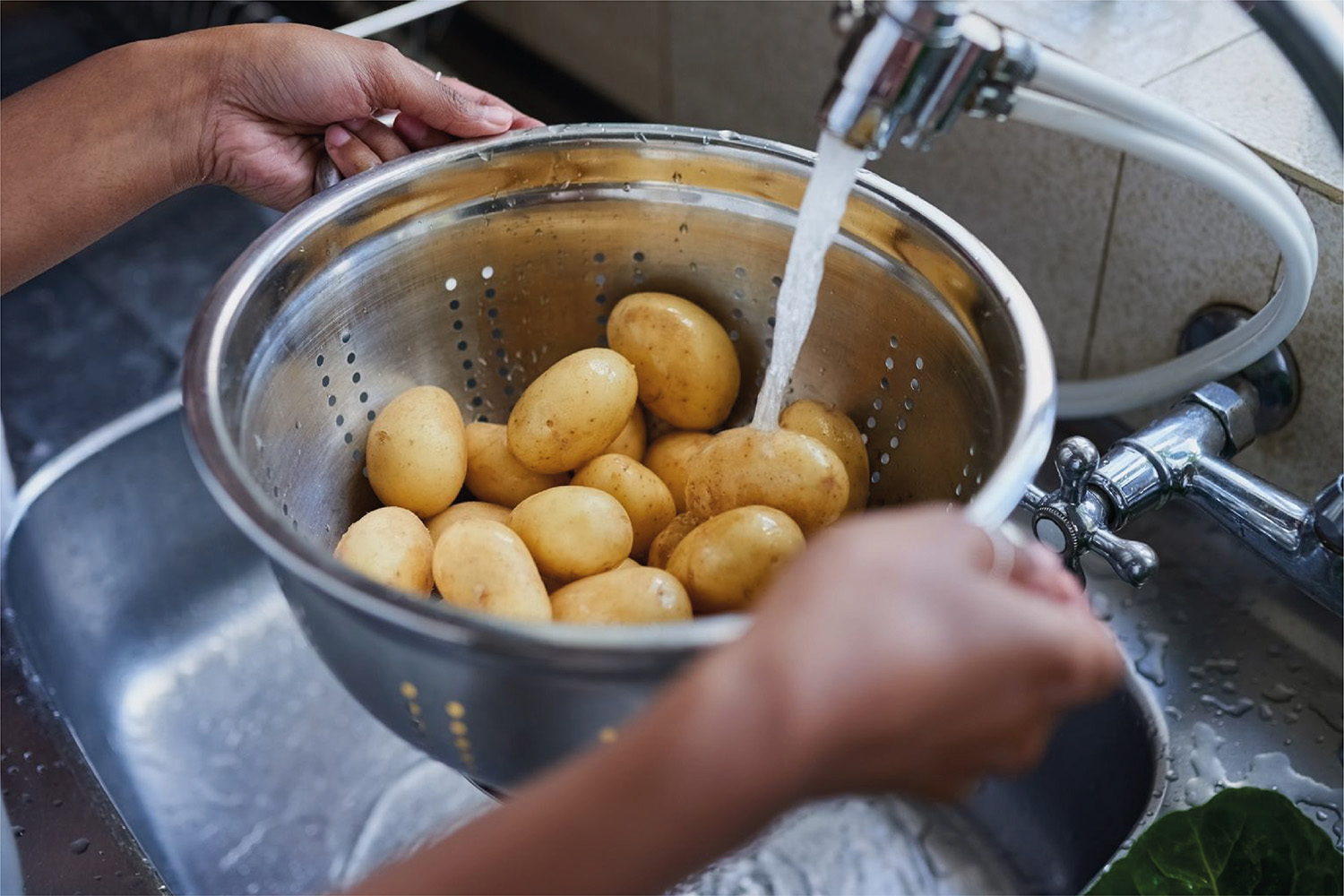 Persona lava papas bajo un chorro de agua de la canilla