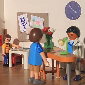 asistente detrás de un escritorio conversa con el padre, mientras el niño juega