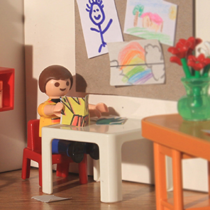 niño juega con libros y juguetes sentado en una mesa pequeña 