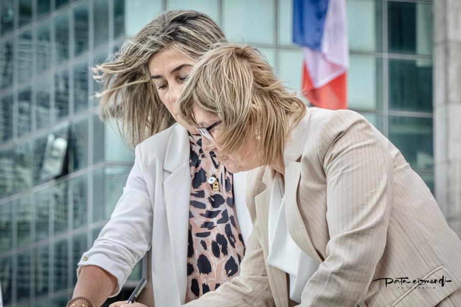 Cristina Lustemberg firma el acta, al fondo el edificio de Presidencia