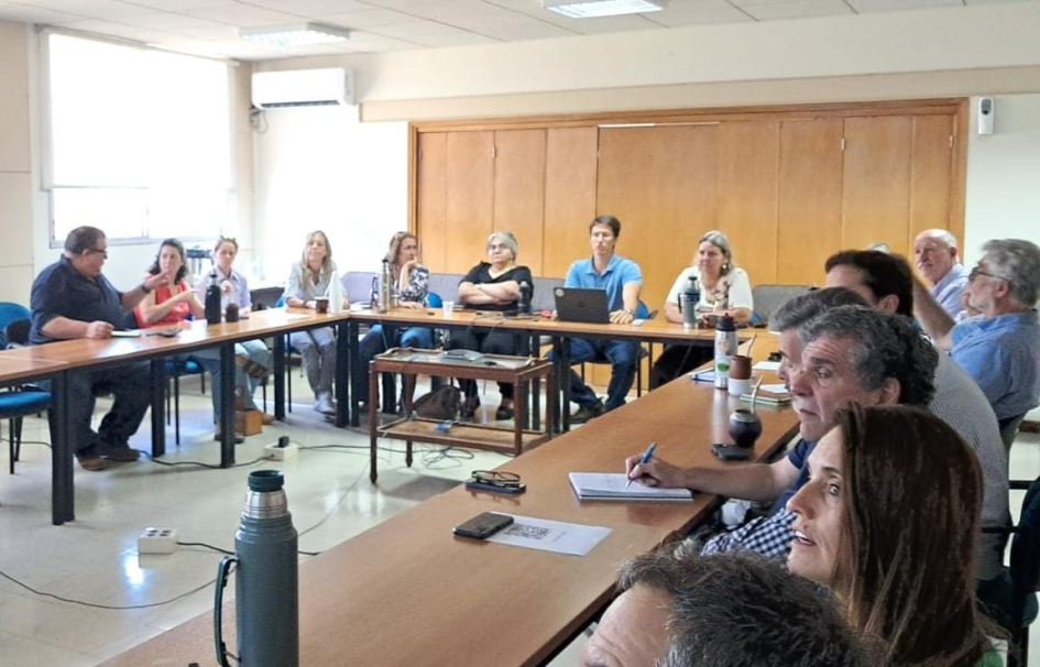 Personas dialogan al rededor de una mesa dispuesta en forma de u