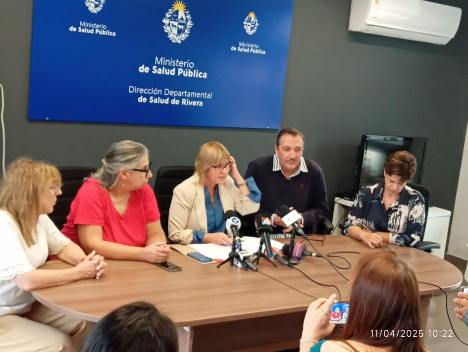 Conferencia de prensa Ministra, directoras generales del MSP y director departamental sentados, micrófonos sobre la mesa