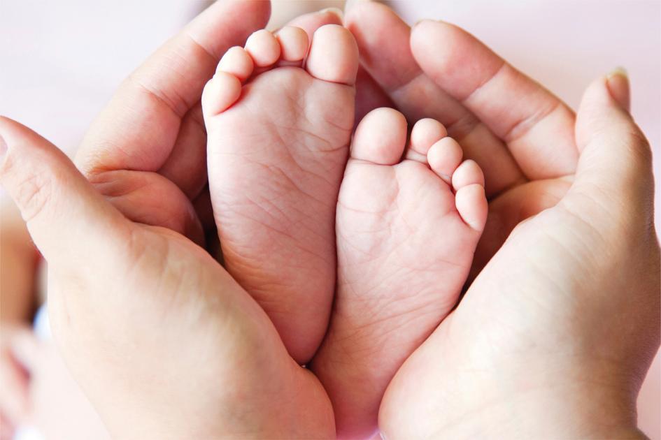 Pies de bebé en manos de persona adulta Pies de bebé en manos de persona adulta