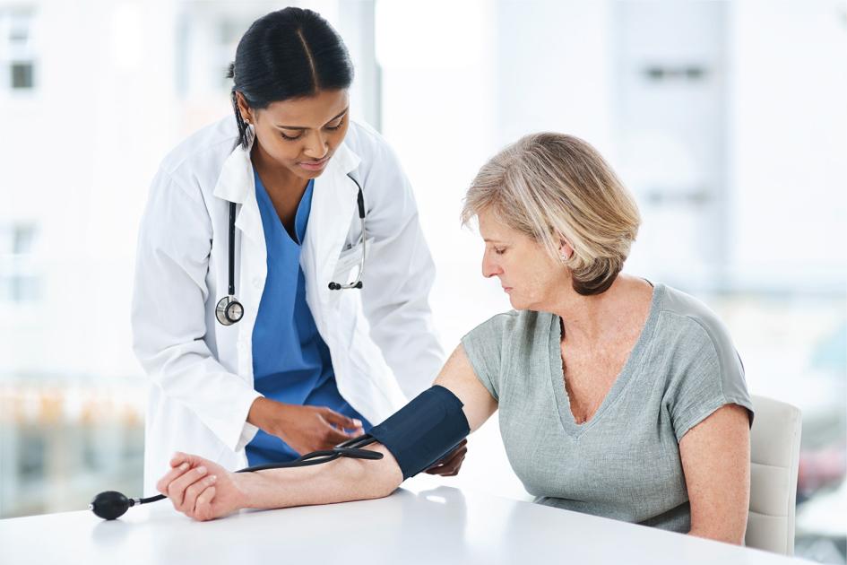 Medición de la presión arterial Una doctora mide la presión arterial de su paciente