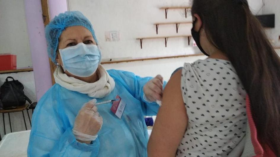 Vacunación comorbilidades Vacunadora dando un vacuna a una persona de espalda