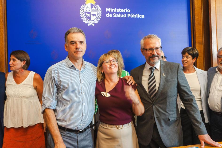 Presidente, Ministra y Subsecretario Presidente, Lustemberg y Briozzo uno al lado del otro, abrazados, con fondo institucional