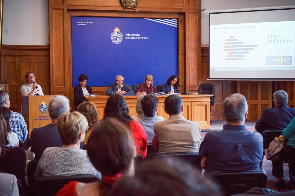 Exposición de datos de tuberculosis 2024 Directora del Programa expone datos, autoridades y público (de espaldas)miran proyección en pantalla