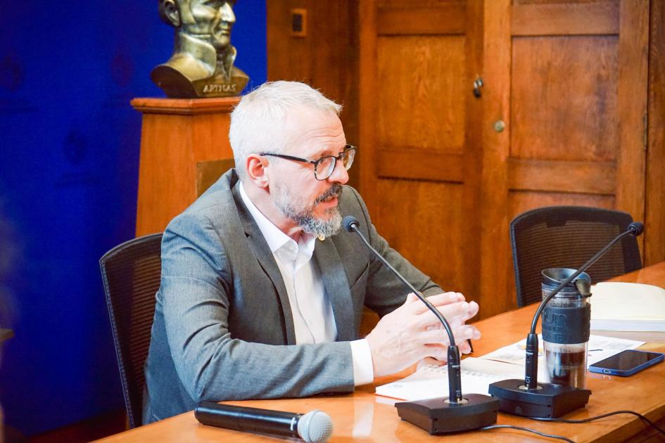 Subsecretario en reunión de la CONASIDA Subsecretario sentado en la mesa de reunión habla al micrófono