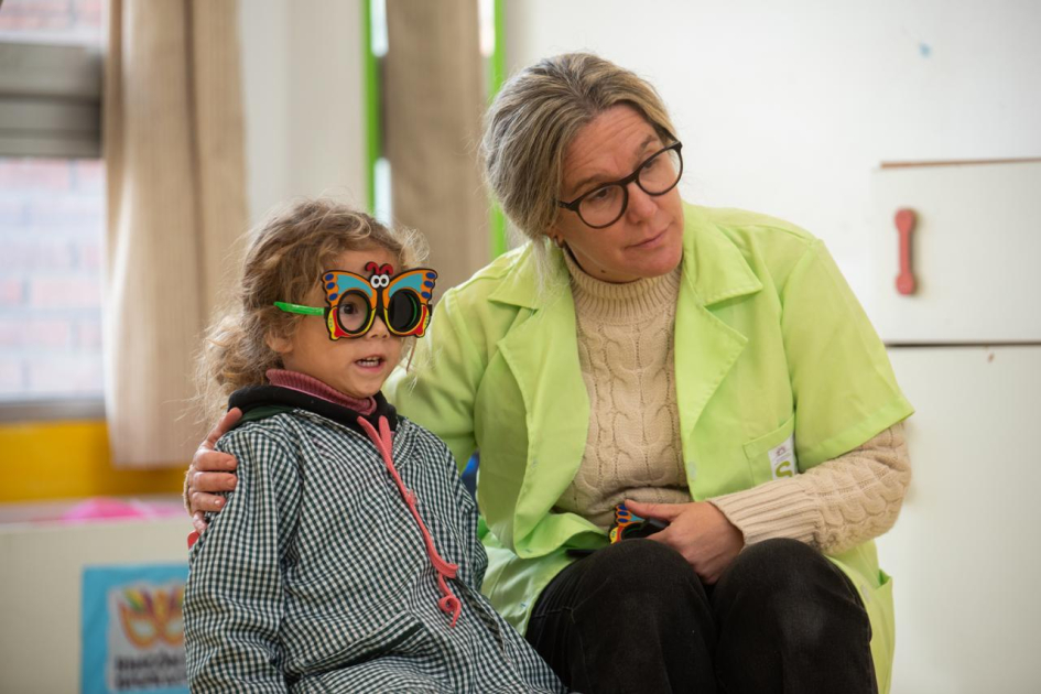 Salud ocular de niñas y niños Niña con lentes mira a lo lejos, asistida por una profesional