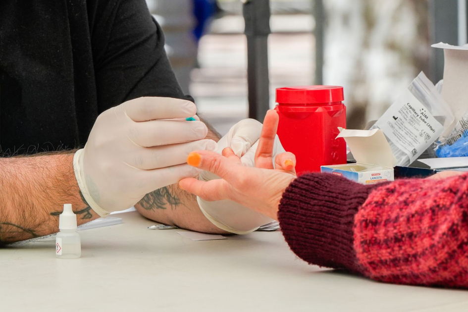 mano enguantada haciendo test de VIH en el dedo de una persona