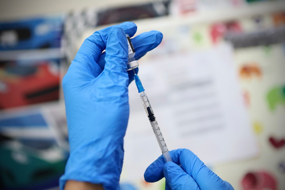 Manos de vacunadora cargan una vacuna