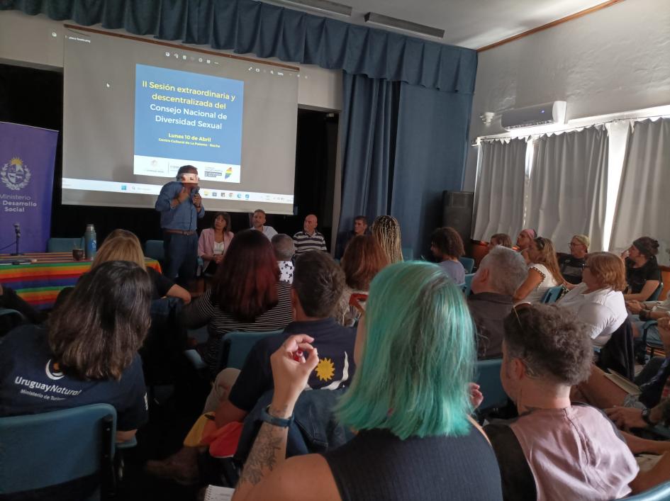 consejo nacional de diversidad sexual personas de espalda miran hacia pantalla y expositores