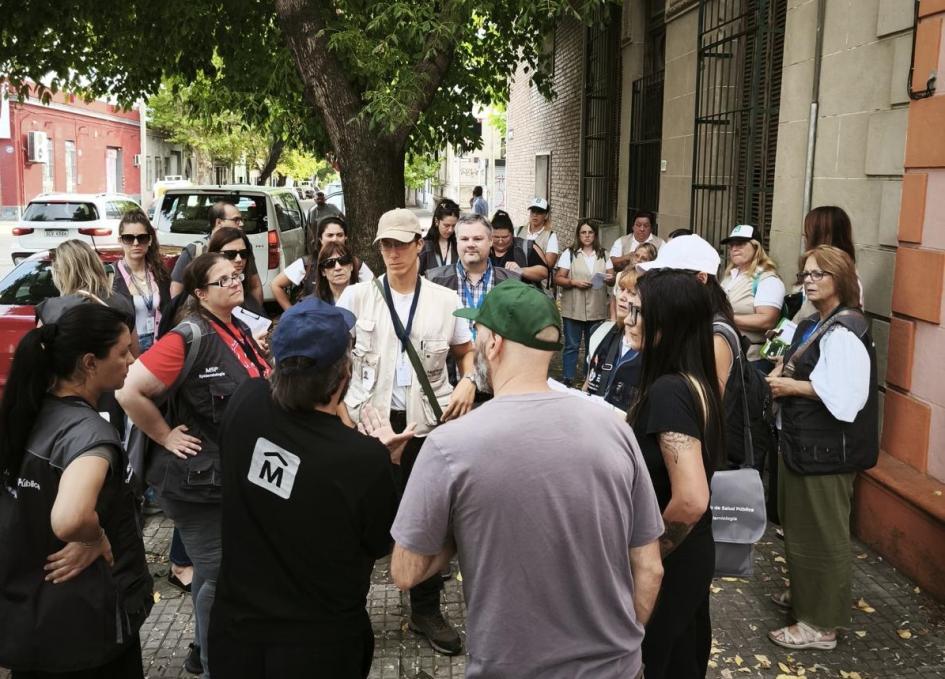 Trabajo de MSP e Intendencia de Montevideo Ronda de varios técnicos y vecinos en una vereda arbolada