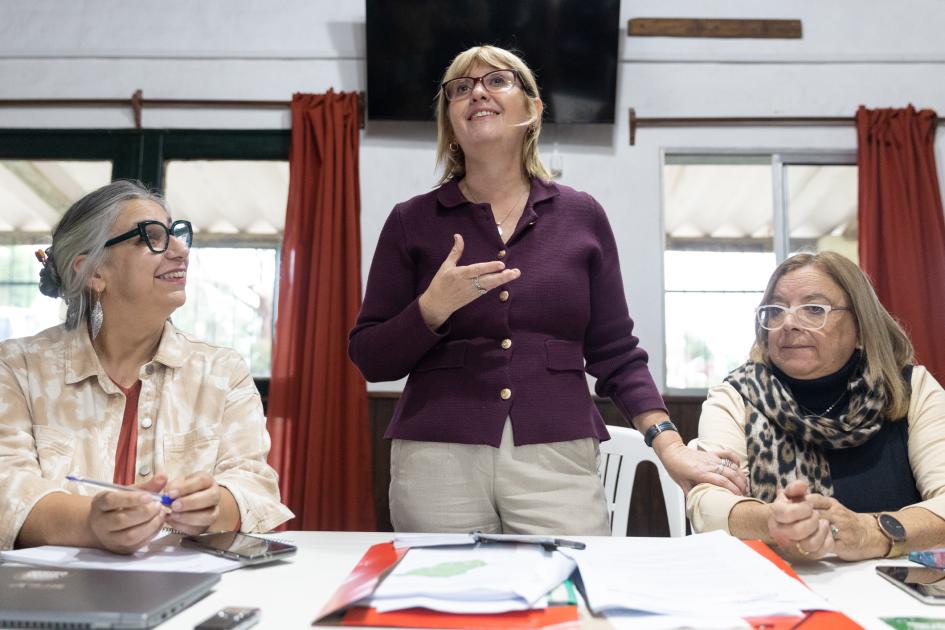 Palabras de Lustemberg en Villa del Rosario Lustemberg de pie detrás de una mesa. A sus lados la directora de DIGECOOR y la DDS de Lavalleja