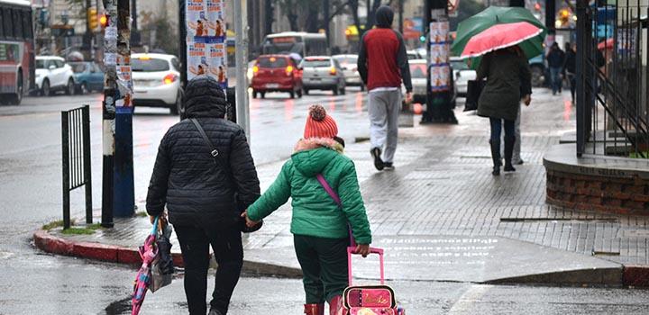 mujer y niña abrigadas cruzando la calle