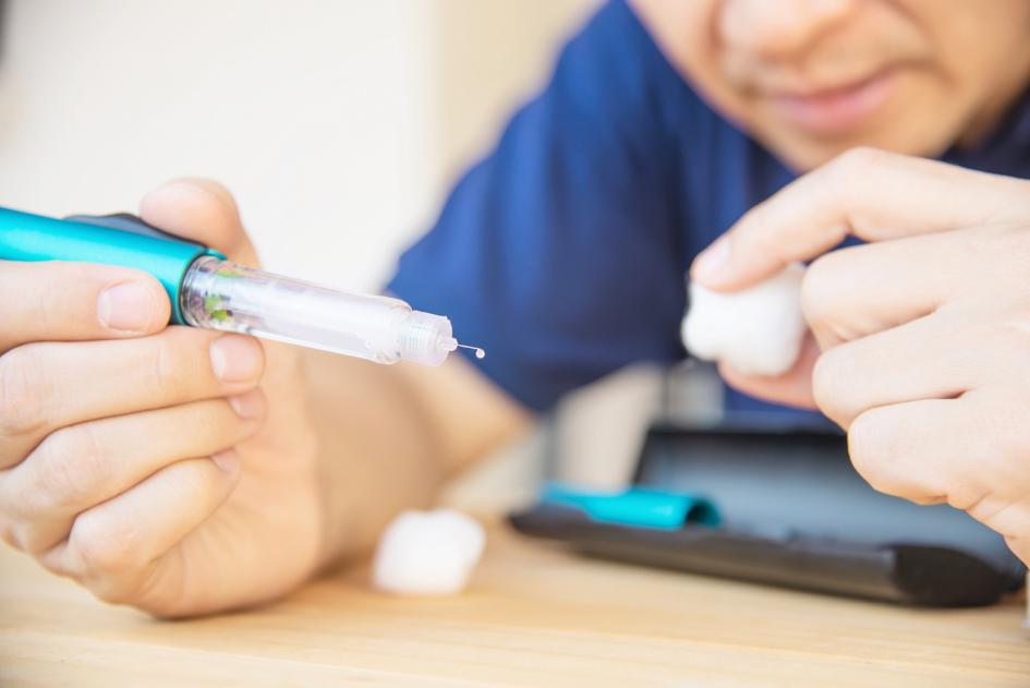 Hombre prepara insulina para inyectarse Hombre prepara insulina para inyectarse