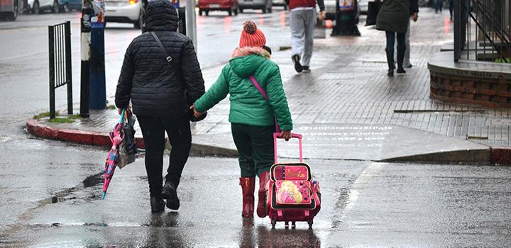 niña y su madre caminando por la calle con lluvia 