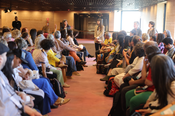 Dos grupos grande de personas dialogan enfrentados. Al fondo 2 mujeres guían la charla.