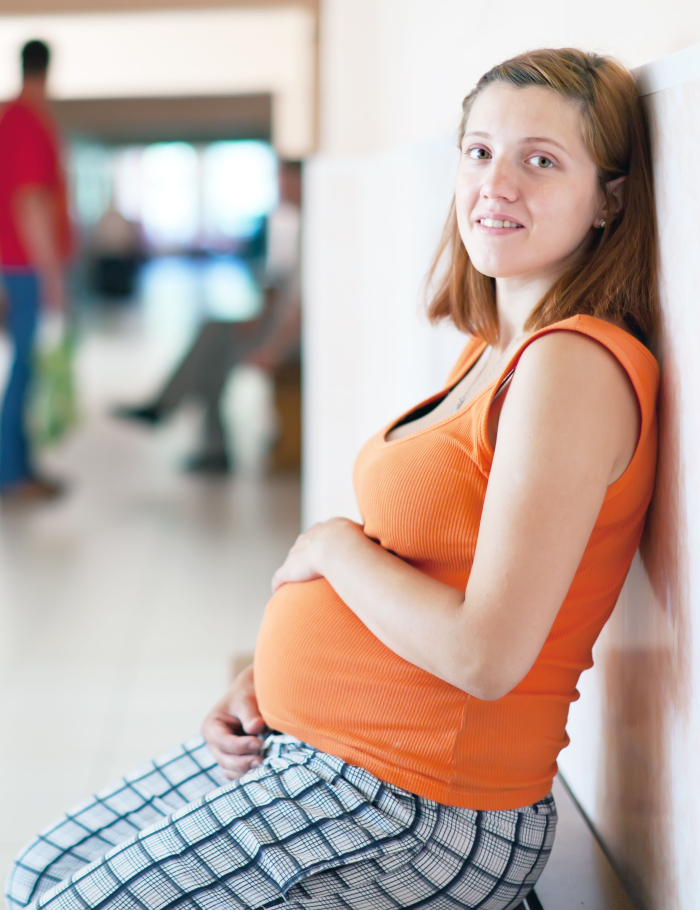 Mujer embarazada sentada contra una pared