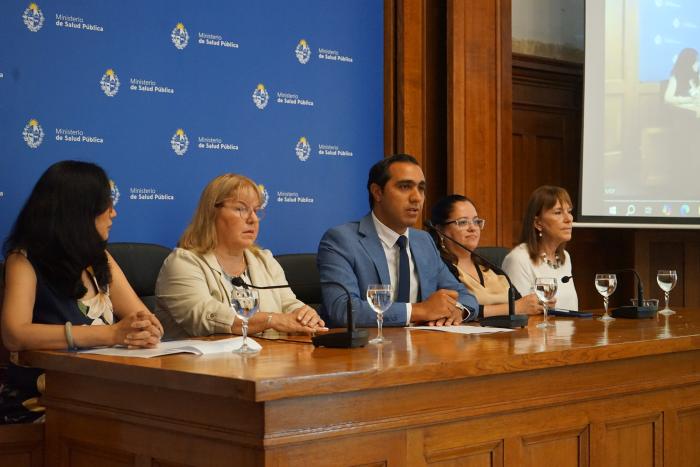 5 autoridades en conferencia sentadas detrás de una mesa, con micrófonos y fondo institucional.