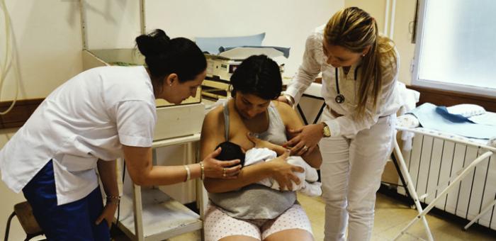 Imagen de madre amamantando con dos enfermeras Imagen de madre amamantando con dos enfermeras