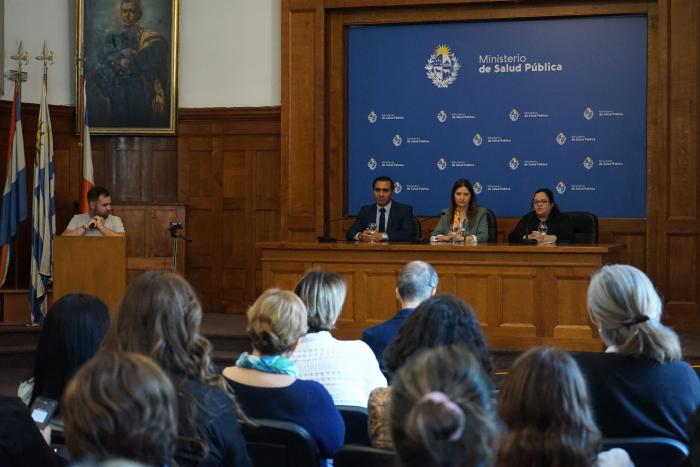 Autoridades en presentación de la guía Público de espaldas y al fondo la mesa de autoridades