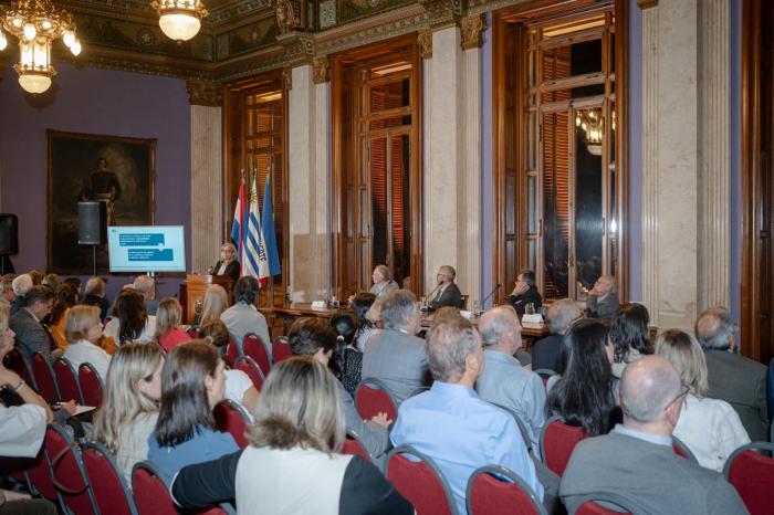 Jornada académica en Palacio Legislativo Sala del Palacio Legislativo con público, mesa de autoridades y expositora de pie