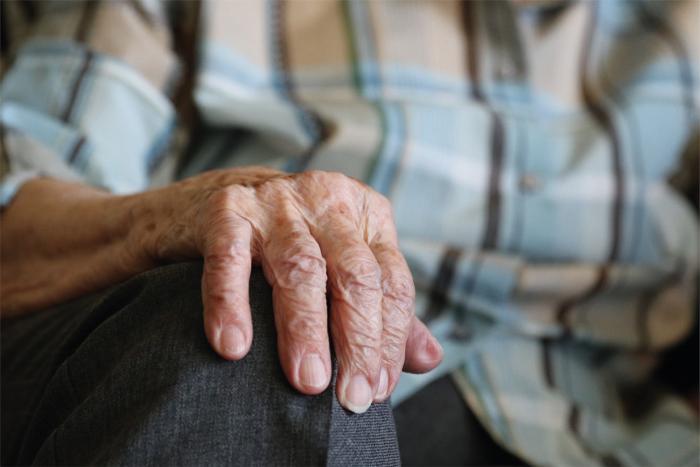 Mano de una persona mayor apoyada en su rodilla