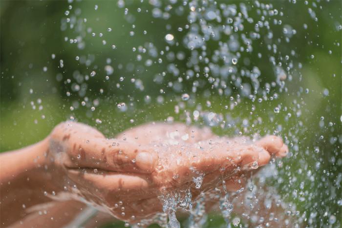 Gotas de agua caen en dos manos