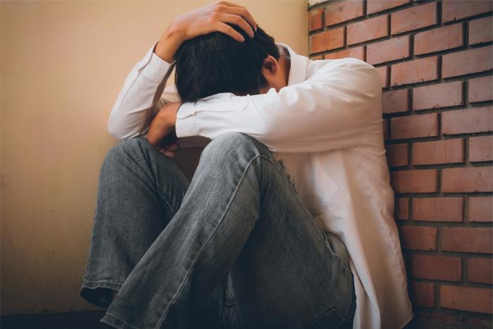 Día mundial contra la depresión Hombre triste sentado en el piso con su cabeza entre las piernas