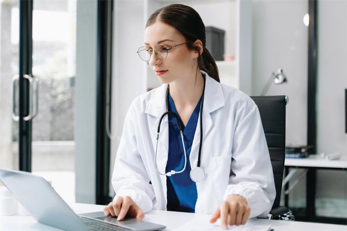 Día Mundial de la Seguridad y la Salud en el Trabajo Mujer con túnica y estetoscopio al cuello trabaja con una computadora