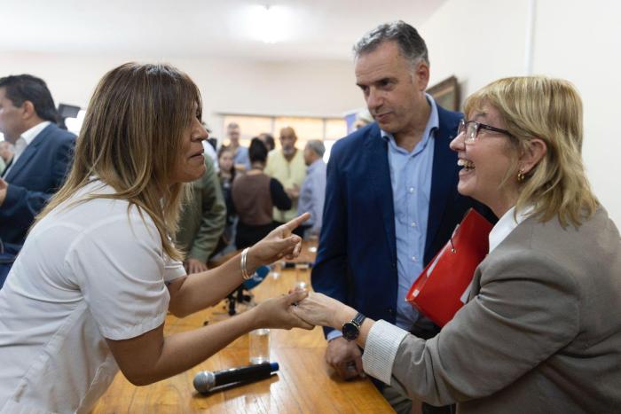 Funcionaria toma la mano de la Ministra, ambas sonríen. A su lado también saluda el Presidente.