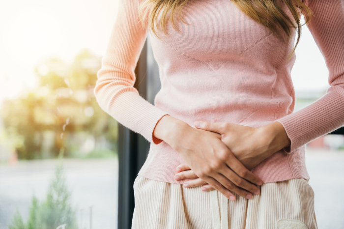 Mujer con manos en el abdomen, que sugirieren dolor causado por endometriosis