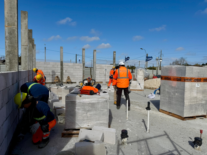 Nueva policlínica de Estación Atlántida en obras grupo de trabajadores de la construcción con cascos y chalecos de seguridad en una obra