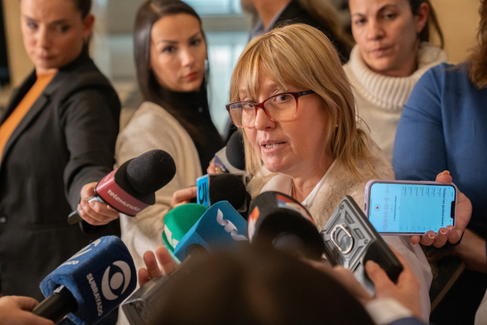 Ministra Lustemberg rodeada de periodistas y micrófonos en rueda de prensa
