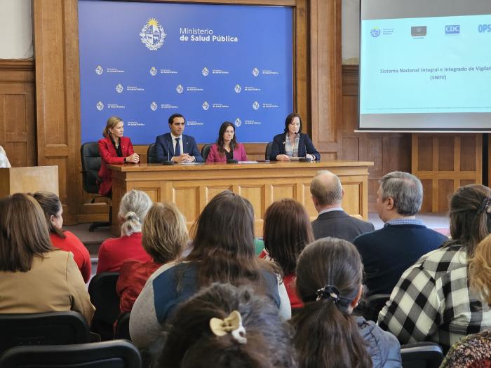 Lanzamiento del proyecto 4 autoridades en conferencia, con fondo institucional y participantes de espaldas a cámara