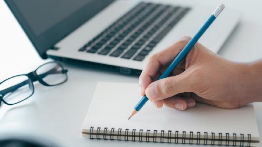 La imagen de una mano anotando en un block de notas