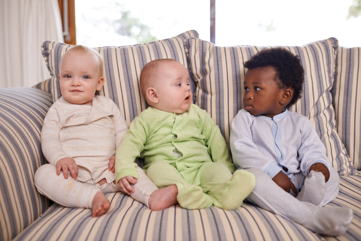 Tres bebés sentados en un sillón