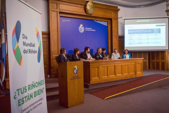 Autoridades sentadas en salón de actos. En primer plano un banner que dice: ¿tus riñones están bien?