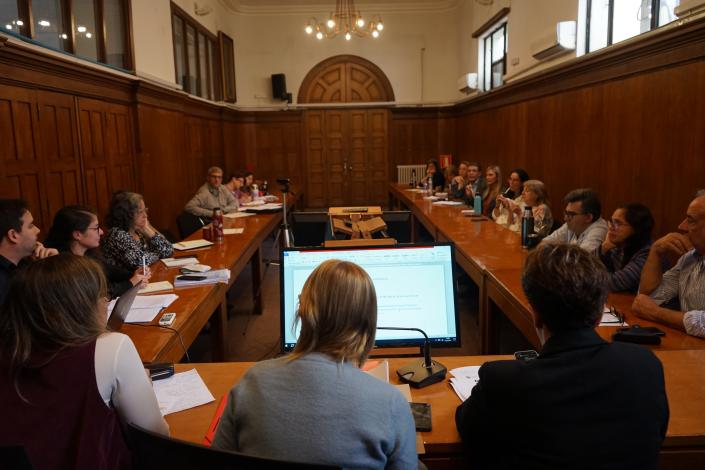 Sala de sesiones con autoridades y técnicos en mesas que forman una U. Ministra en la cabecera