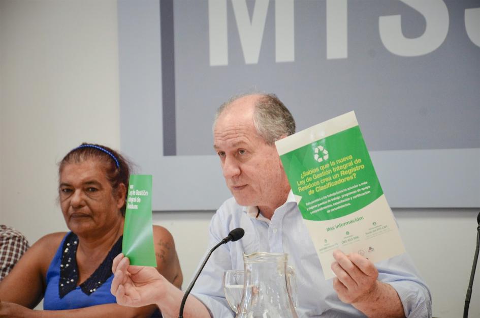 Murro sosteniendo un folleto y un adhesivo sobre la Ley de Gestión de Residuos