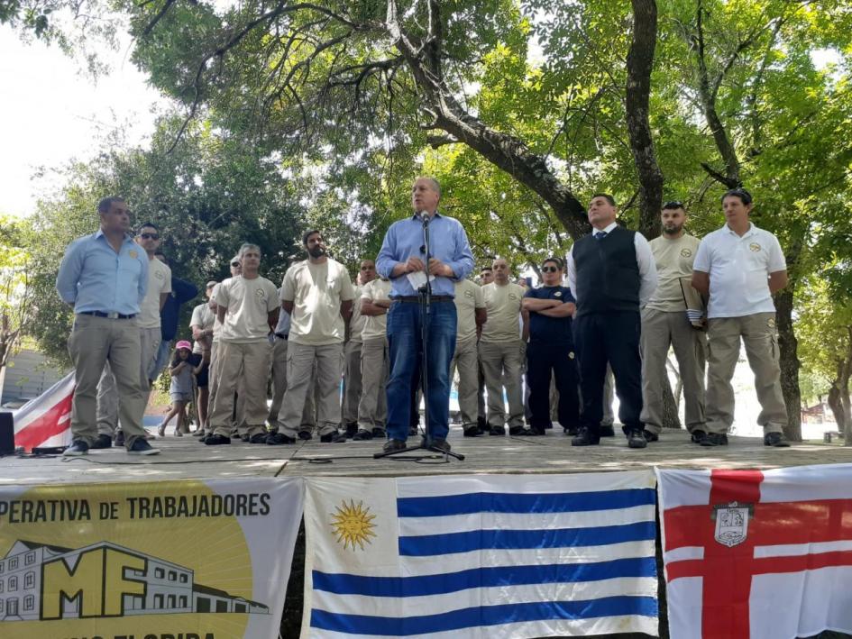 Murro Molina Florida Ministro de Trabajo rodeado por cooperativistas en un estrado, mientras da un discurso