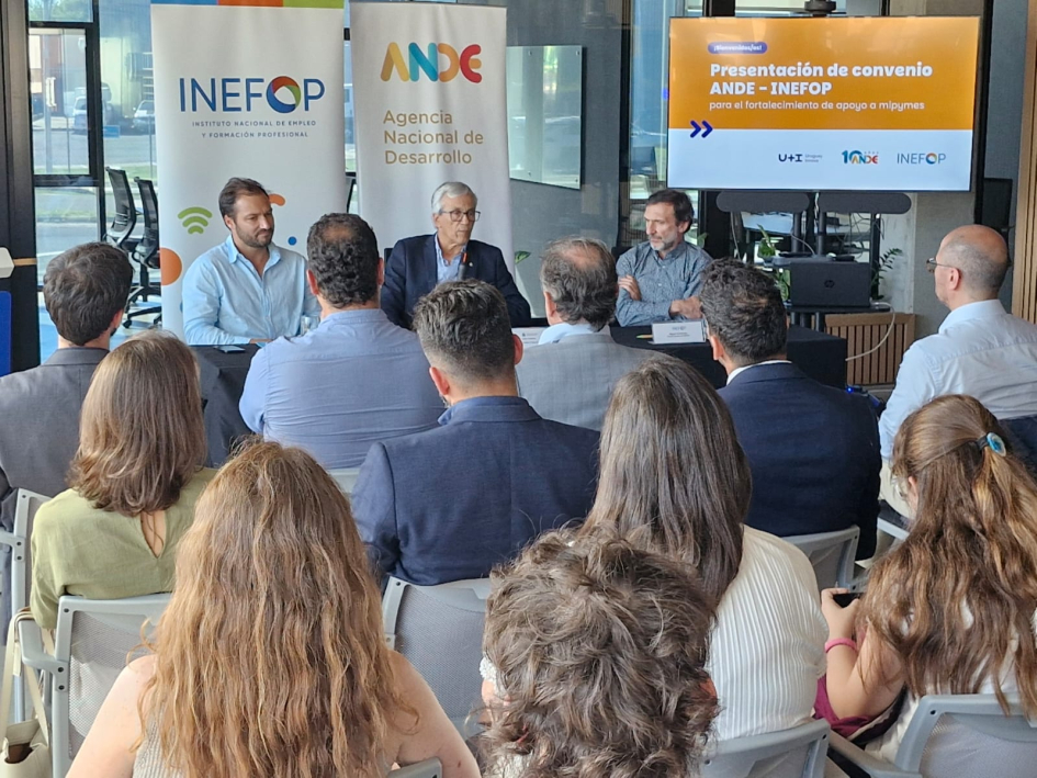 Imagen tomada desde el fondo de la sala, con público de espaldas y autoridades durante la exposición