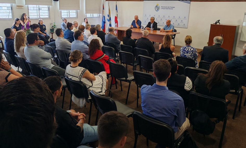 Imagen desde el fondo del salón, con público presente y autoridades en la mesa